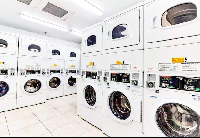 laundry area featuring stacked washer / drying machine, washer and dryer, and light tile patterned floors