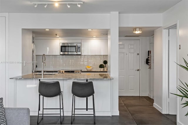 kitchen featuring white cabinetry, light stone countertops, stainless steel appliances, and sink