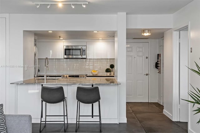540 Brickell Key Dr Unit 1519, Miami, FL 33131 - kitchen featuring a breakfast bar area, a sink, a peninsula, stainless steel appliances, and white cabinetry