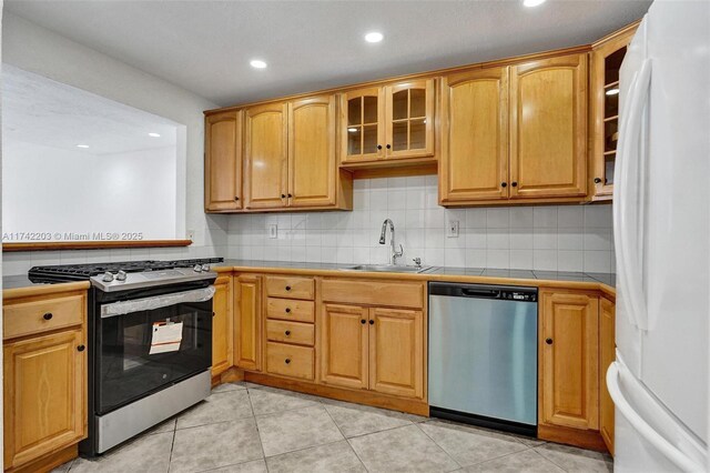 kitchen with recessed lighting, tile countertops, a sink, glass insert cabinets, and appliances with stainless steel finishes