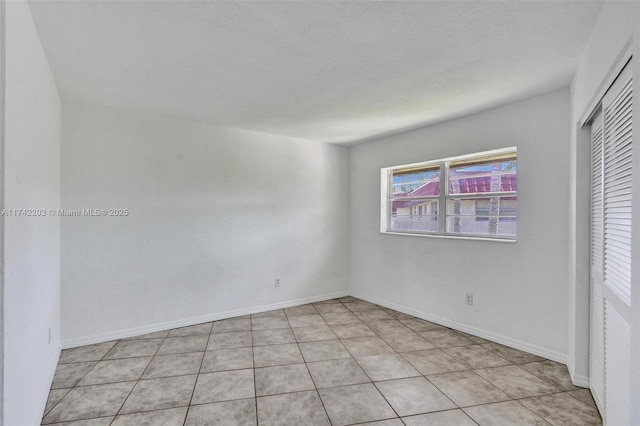 unfurnished bedroom featuring baseboards, a closet, and light tile patterned floors