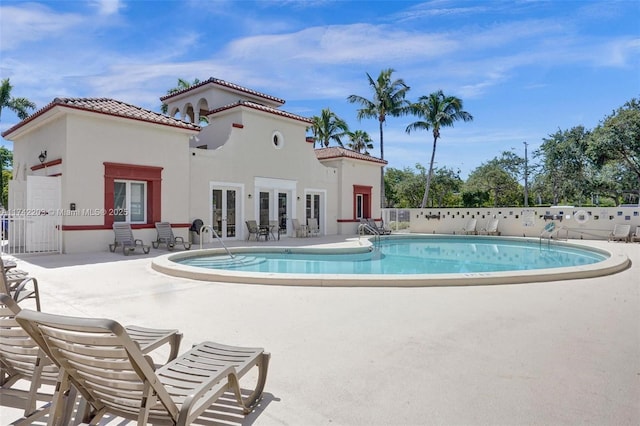 pool featuring fence, a patio area, and french doors