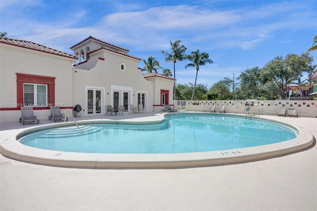 community pool featuring fence, a patio area, and french doors