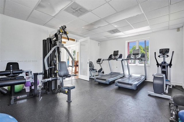 gym featuring baseboards and a drop ceiling