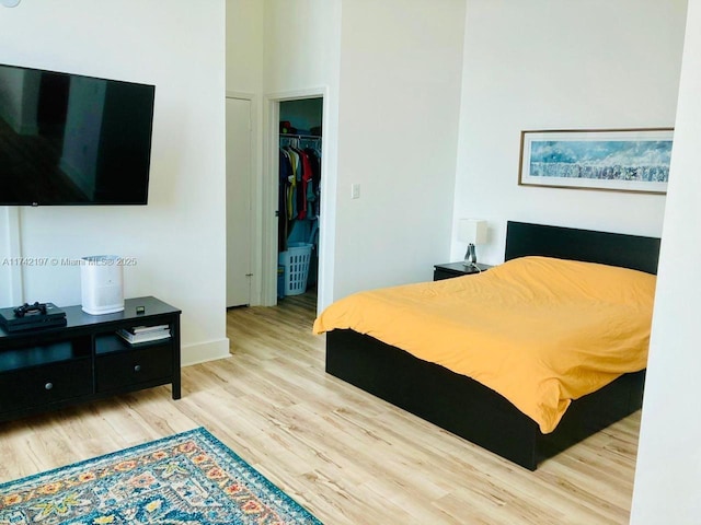 bedroom featuring a spacious closet, light hardwood / wood-style floors, and a closet