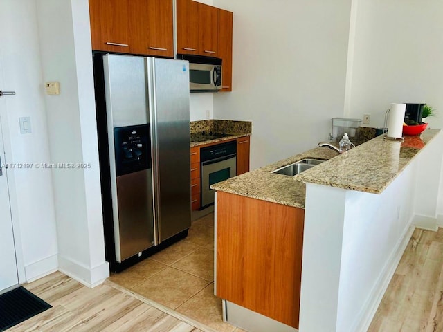 kitchen with light stone counters, sink, kitchen peninsula, and appliances with stainless steel finishes