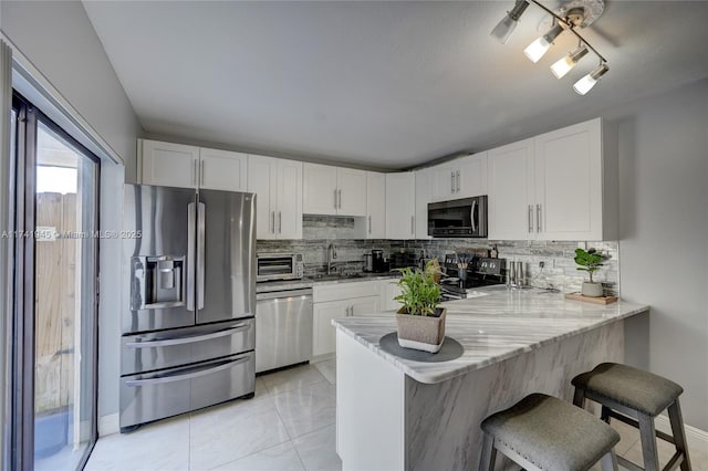 kitchen with a breakfast bar, stainless steel appliances, kitchen peninsula, and white cabinets