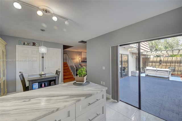 kitchen with pendant lighting, white cabinets, light stone counters, and light tile patterned floors