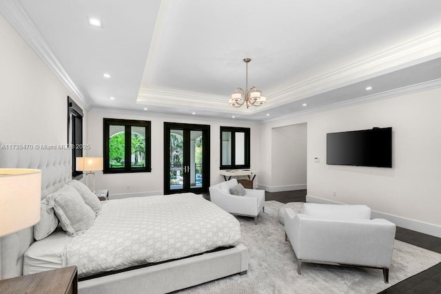 bedroom featuring french doors, light hardwood / wood-style flooring, ornamental molding, a tray ceiling, and a notable chandelier