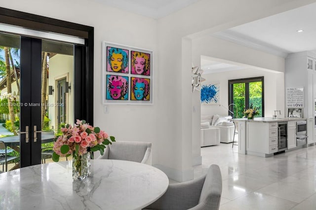 dining area with sink, crown molding, light tile patterned floors, french doors, and beverage cooler