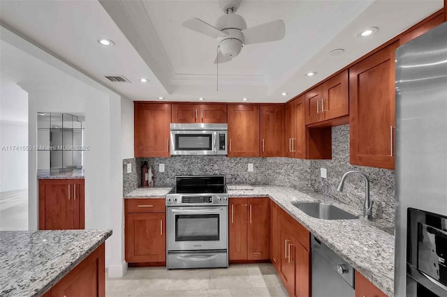 kitchen featuring sink, appliances with stainless steel finishes, light stone counters, tasteful backsplash, and a tray ceiling