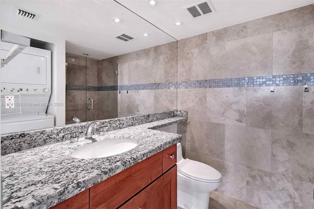 2000 Towerside Ter Unit 910, Miami, FL 33138 - full bathroom with stacked washing machine and dryer, tile walls, a shower stall, vanity, and toilet
