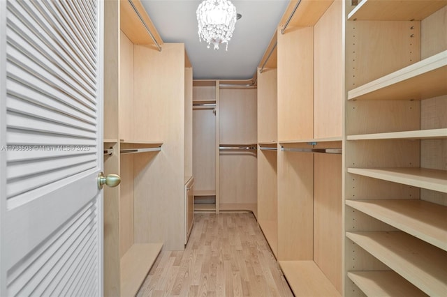 walk in closet featuring a notable chandelier and light wood-type flooring