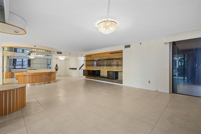 unfurnished living room with an inviting chandelier and light tile patterned floors