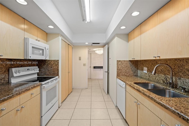 kitchen with sink, dark stone countertops, white appliances, and light tile patterned floors