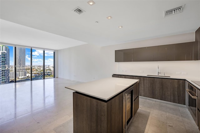 kitchen featuring sink, expansive windows, a center island, stainless steel oven, and dark brown cabinets