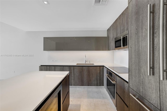 kitchen with appliances with stainless steel finishes, sink, and dark brown cabinetry