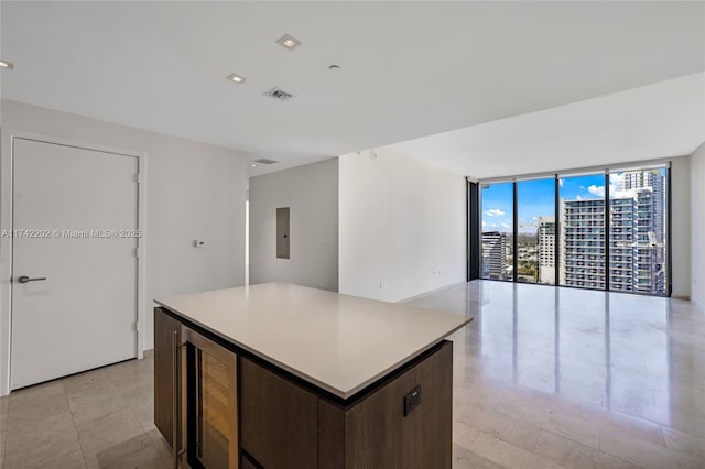 kitchen with electric panel, floor to ceiling windows, wine cooler, dark brown cabinetry, and a kitchen island