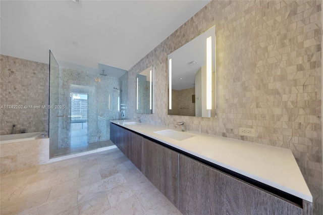 bathroom with vanity, shower with separate bathtub, and tile walls