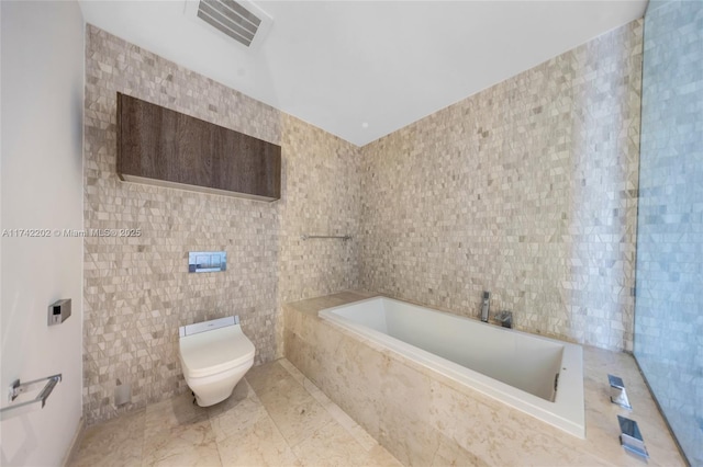 bathroom with tiled bath, tile walls, and toilet