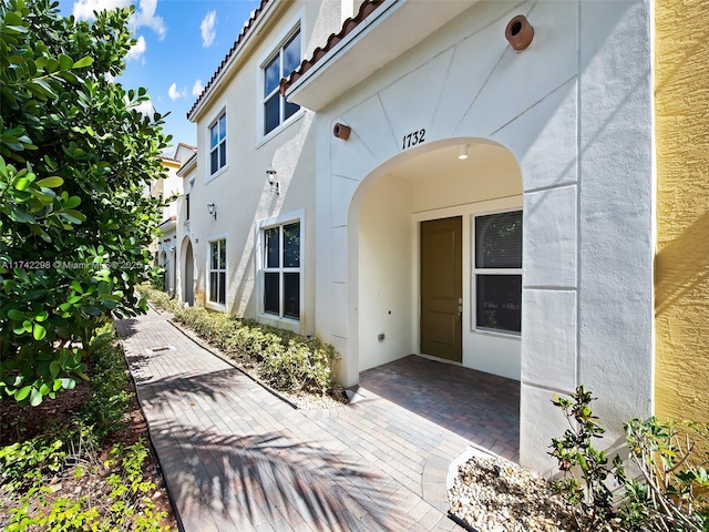 property entrance with a tile roof and stucco siding