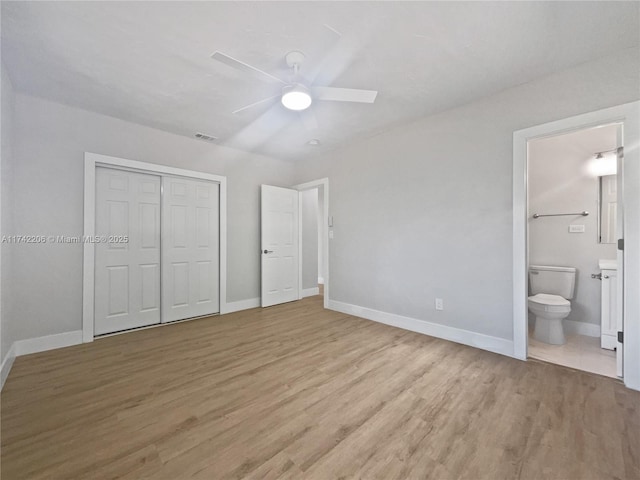 unfurnished bedroom featuring ceiling fan, connected bathroom, a closet, and light wood-type flooring