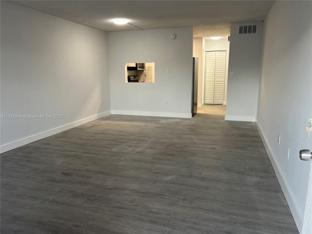 empty room with dark hardwood / wood-style floors and a textured ceiling