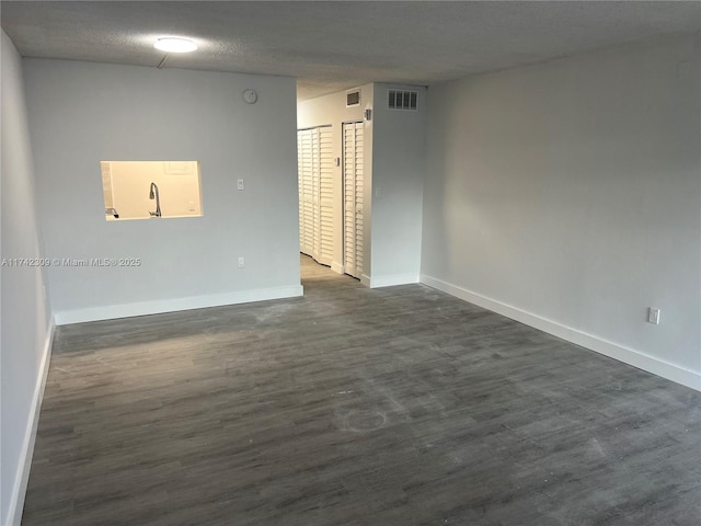 spare room with dark hardwood / wood-style flooring and a textured ceiling