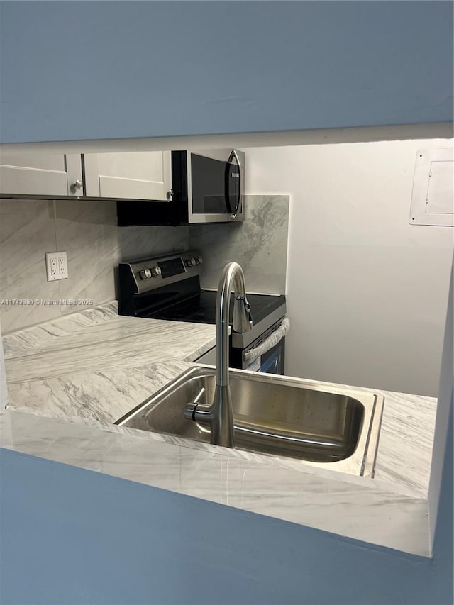 kitchen with appliances with stainless steel finishes, sink, white cabinets, and decorative backsplash