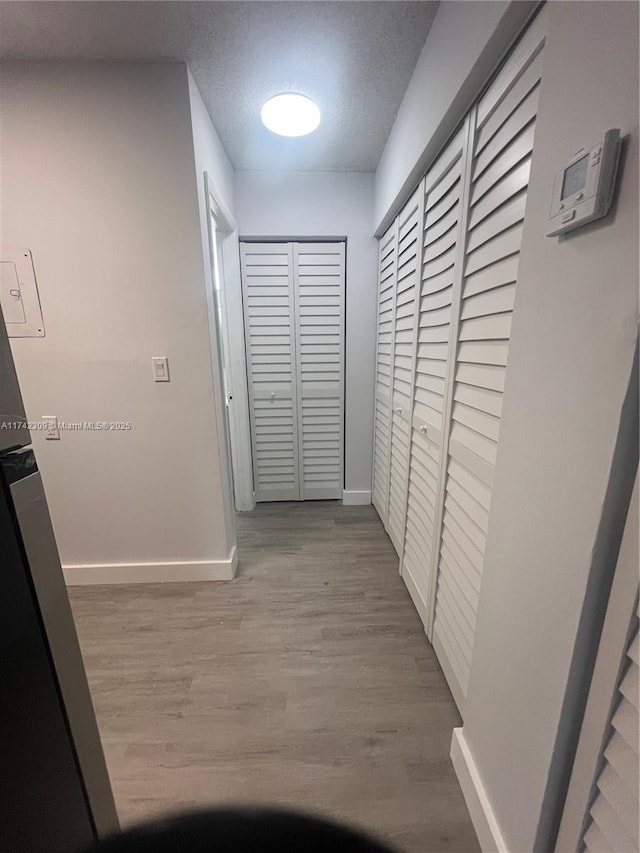 hallway with light hardwood / wood-style floors and a textured ceiling