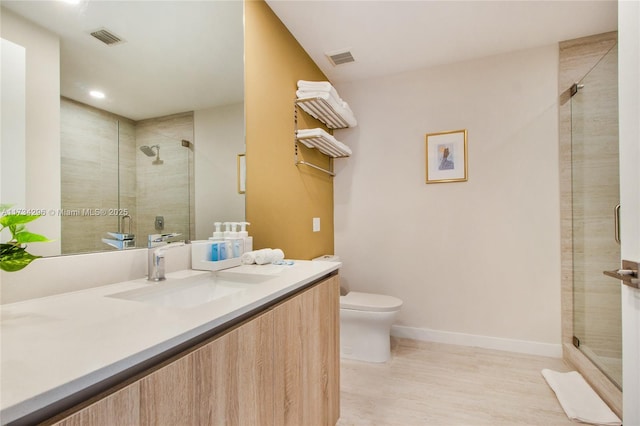 bathroom featuring vanity, a shower with shower door, and toilet