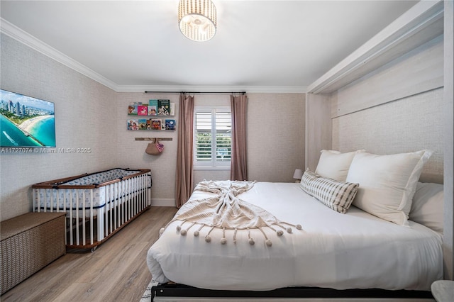 bedroom featuring light wood-style floors, ornamental molding, and baseboards