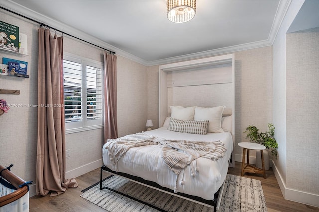 bedroom with ornamental molding, wallpapered walls, baseboards, and wood finished floors