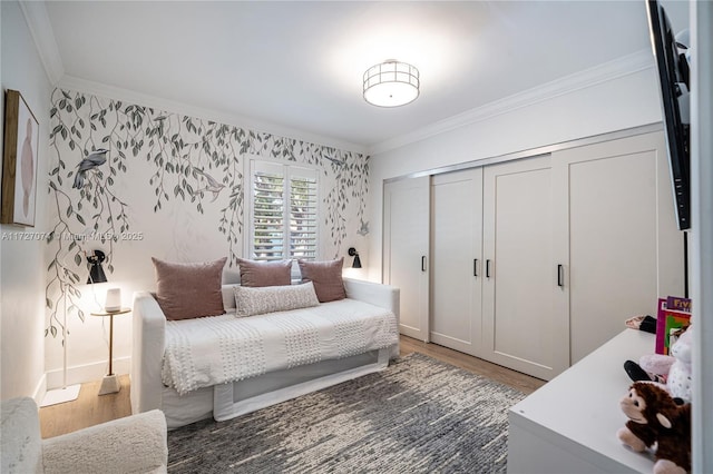 bedroom featuring crown molding, a closet, dark wood finished floors, and wallpapered walls