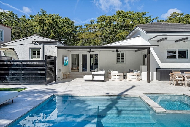 rear view of property featuring ceiling fan, a patio area, a pool with connected hot tub, outdoor lounge area, and stucco siding