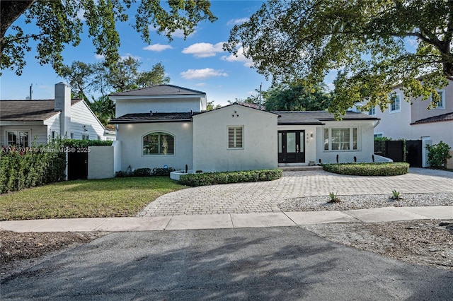 view of front facade featuring french doors, fence, a front lawn, and stucco siding