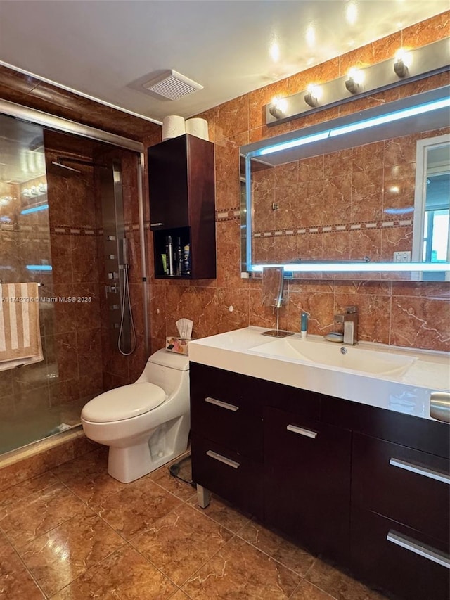 bathroom featuring a shower with door, vanity, tile walls, and toilet