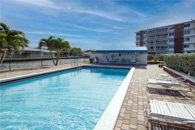 view of pool with a water view and a patio