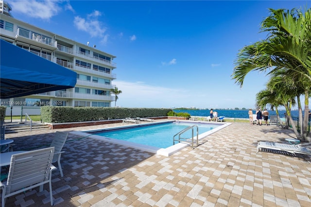 view of pool with a water view and a patio area