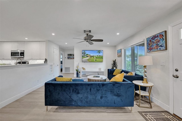 living room with ceiling fan and light hardwood / wood-style flooring