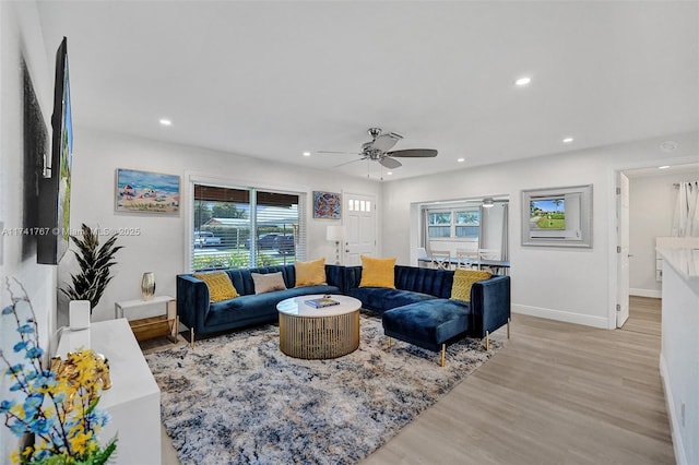 living room featuring ceiling fan, plenty of natural light, and light hardwood / wood-style floors