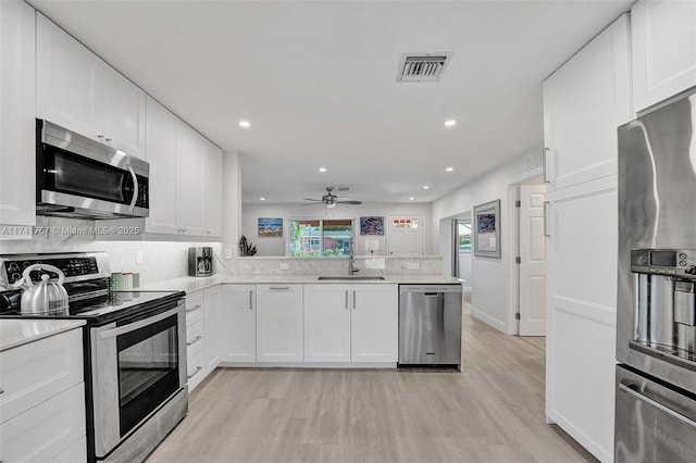 kitchen featuring sink, light hardwood / wood-style flooring, stainless steel appliances, white cabinets, and kitchen peninsula