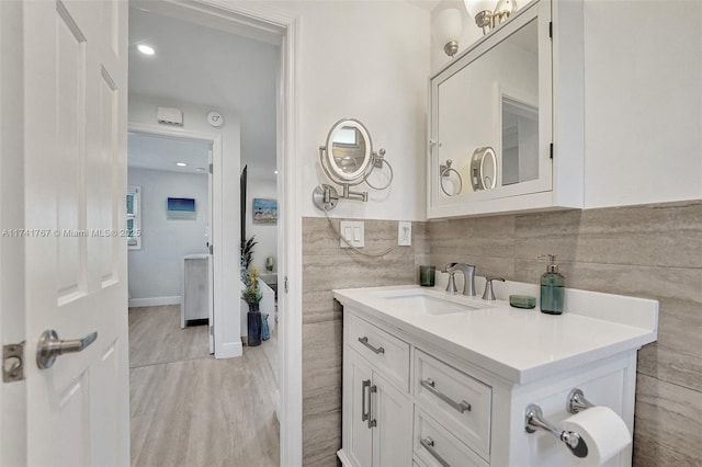 bathroom with vanity, wood-type flooring, and tile walls