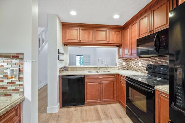 kitchen with sink, light stone counters, light hardwood / wood-style floors, decorative backsplash, and black appliances