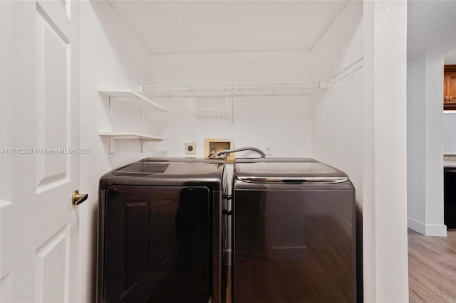 clothes washing area featuring washing machine and dryer and light hardwood / wood-style flooring