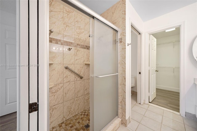 bathroom with tile patterned flooring, toilet, and a shower with shower door