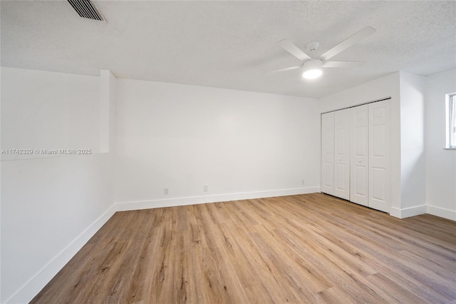 unfurnished bedroom with ceiling fan, a textured ceiling, light hardwood / wood-style floors, and a closet