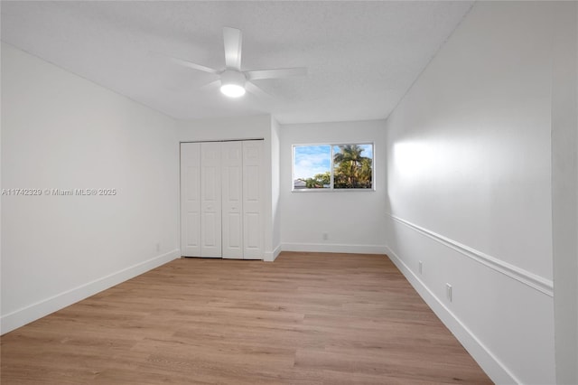 unfurnished bedroom with ceiling fan, a textured ceiling, a closet, and light wood-type flooring