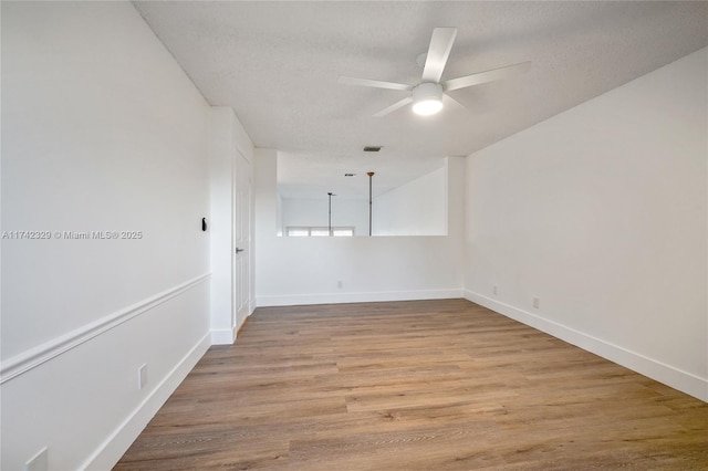 spare room featuring a textured ceiling, light hardwood / wood-style flooring, and ceiling fan