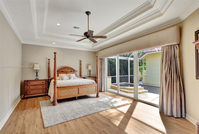 bedroom featuring access to exterior, visible vents, a tray ceiling, and light wood-style floors